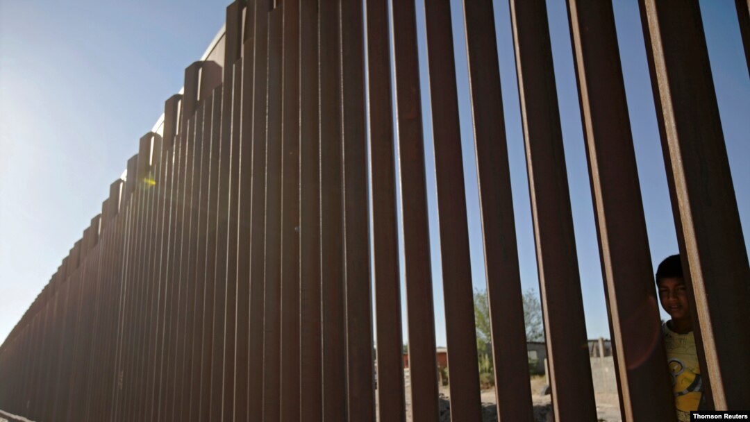 FILE - A child looks through the bars of a wall from the side of Ciudad Juarez, Mexico, in this picture taken on the side of El Paso, Texas, U.S.A., May, 25, 2019.