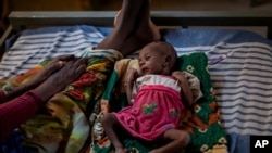 FILE - In this May 11, 2021, photo, Abeba Gebru, 37, from the village of Getskimilesley, sits with her malnourished daughter, Tigsti Mahderekal, 20 days old, in the treatment tent of a medical clinic in Abi Adi, Tigray region, Ethiopia. 