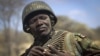 Kenyan army soldier Nicholas Munyanya, wearing a helmet on which is written in Kiswahili "Tea in Kismayo", referring to a key strategic Somali town under the control of al-Shabab, checks his ammunition belt near the town of Dhobley in Somalia, Feb. 21, 2012. 