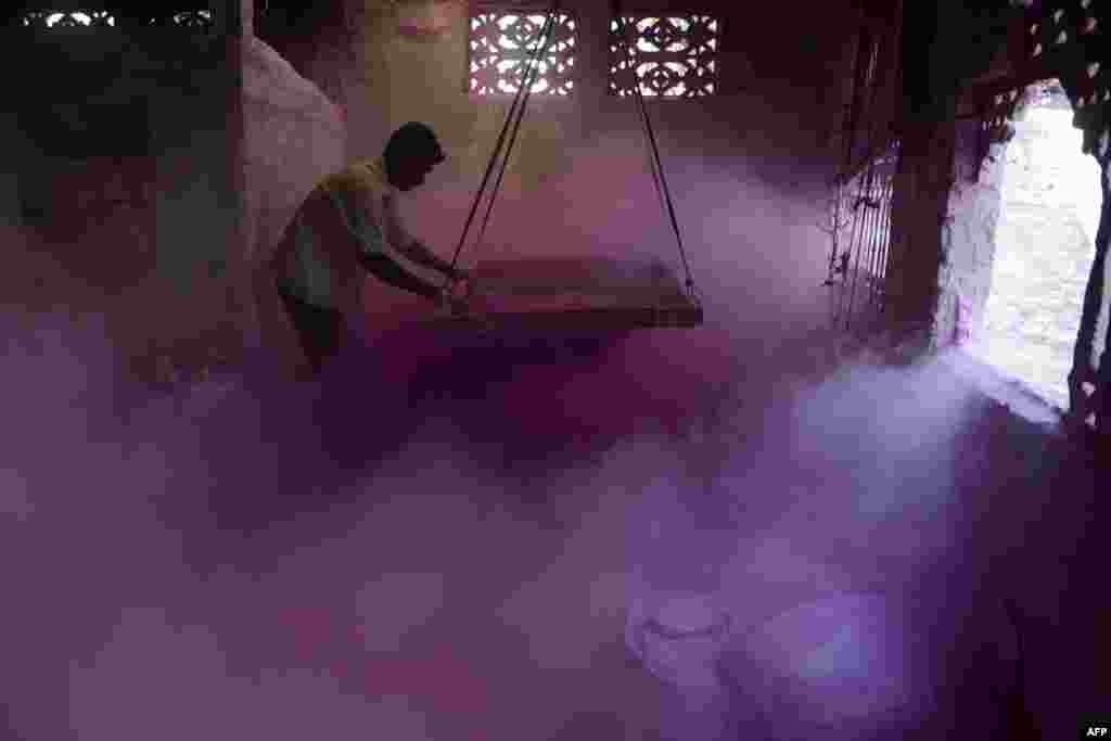 An Indian laborer sifts colored powder, known as 'gulal', to be used during the forthcoming spring festival of Holi, inside a factory at Fulbari village on the outskirts of Siliguri.