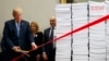 President Donald Trump cuts a ceremonial red tape during an event on federal regulations at the White House, Dec. 14, 2017, in Washington. "Let's cut the red tape, let's set free our dreams," Trump said, next to stacks of paper that he said represented the size of the federal regulatory code.