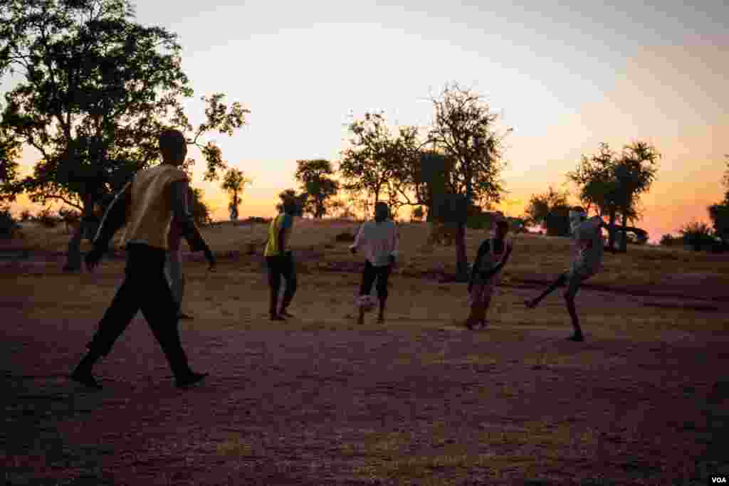 As night falls, a group of boys from the caves come out of hiding and play football in the brief moments of peace before dark. (Adam Bailes/VOA News)