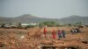FILE - Residents walk past Adi Harush Refugee camp in Mai Tsberi town in Tigray Region, Ethiopia, June 26, 2021.