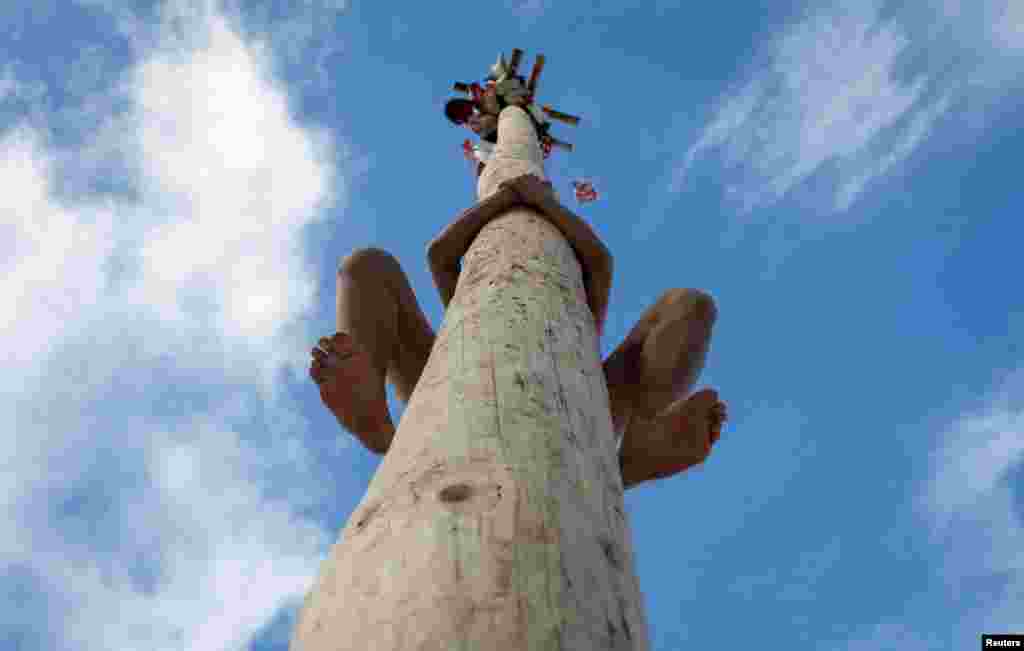 A man climbs up a wooden pole to get a prize during celebration of Maslenitsa, or Pancake Week, a pagan holiday marking the end of winter, near Rumyantsevo, Moscow region, Russia.