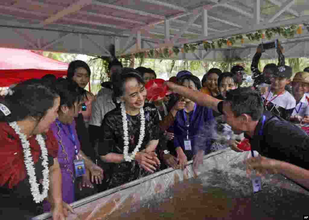 Myanmar's State Counselor Aung San Suu Kyi, center, is doused with water by a man as she takes part in the last day of the country's traditional water festival, also known as Myanmar New Year, in Naypyitaw.