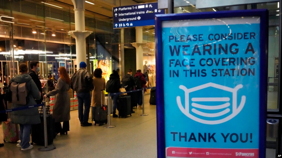 FILE - A sign asking people to wear face coverings to curb the spread of coronavirus is displayed at London St Pancras International rail station, in London, the Eurostar hub to travel to European countries, Dec. 17, 2021. 