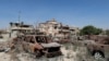 FILE - Burnt cars are seen next to buildings damaged during clashes between military forces loyal to Libya's eastern government and the Shura Council of Libyan Revolutionaries, an alliance of former anti-Gadhafi rebels who have joined forces with the Islamist group Ansar al-Sharia, in Benghazi, April 24, 2016.