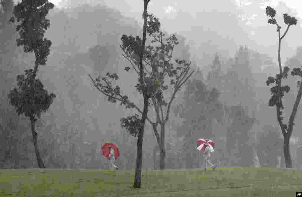 Course marshals carry umbrellas as they make their way toward shelter during a heavy rain at the HSBC Women's Champions golf tournament at Sentosa Golf Club's Tanjong course in Singapore.