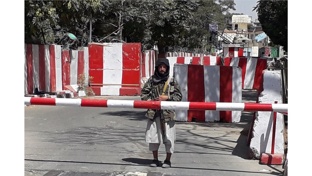 A Taliban fighter stands guard at the entrance of the police headquarters in Ghazni on August 12, 2021, as Taliban move closer to Afghan capital after taking Ghazni city.