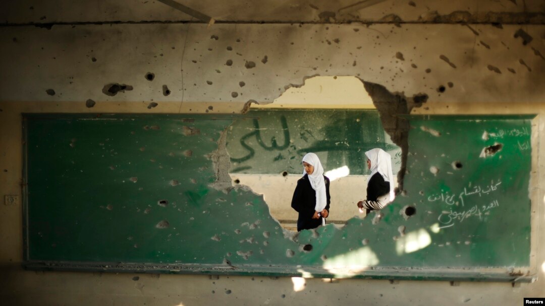 Palestinian students look inside a classroom that witnesses said was shelled by Israel during its offensive, on the first day of the new school year east of Gaza City September 14, 2014.