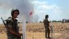FILE - Turkish soldiers stand guard on the Turkish side of the border in Suruc as smoke rises in the background from the Syrian town of Kobani. 