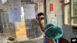 A medical worker checks a person's temperature at the Matanda Hospital in Butembo, Congo, where the first case of Ebola died Feb. 11, 2021, and a second case was recorded in Congo's North Kivu province after a 60-year-old woman died.