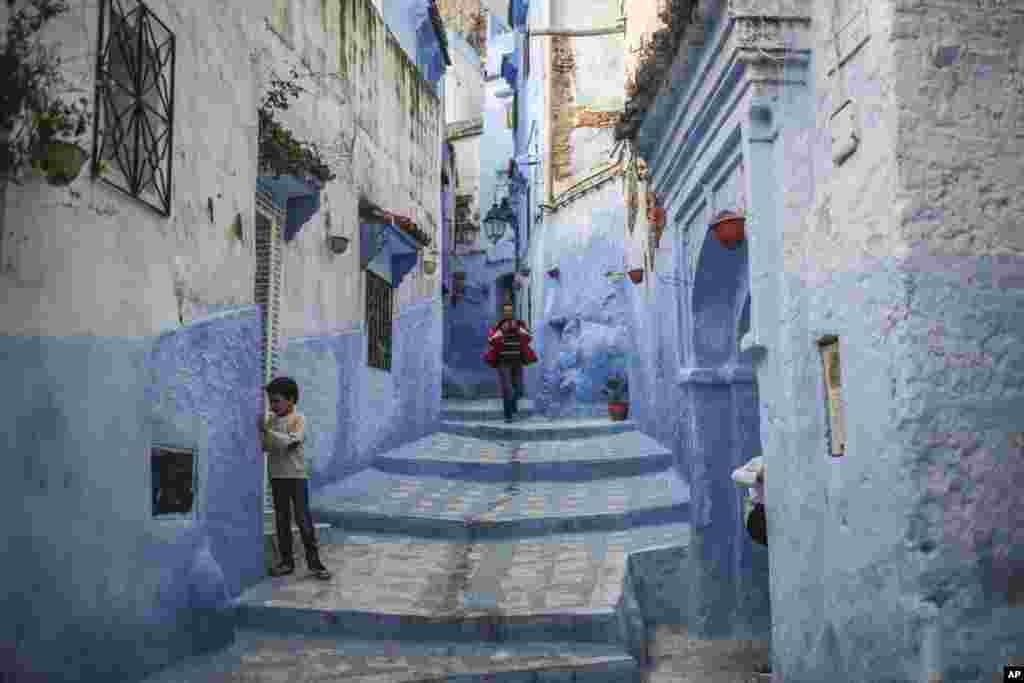 A boy plays outside his house while a man walks down an alleyway in the Medina of Chefchaouen, a picturesque town well-known for its blue painted houses and alleyways, in northern Morocco, April 29, 2017.