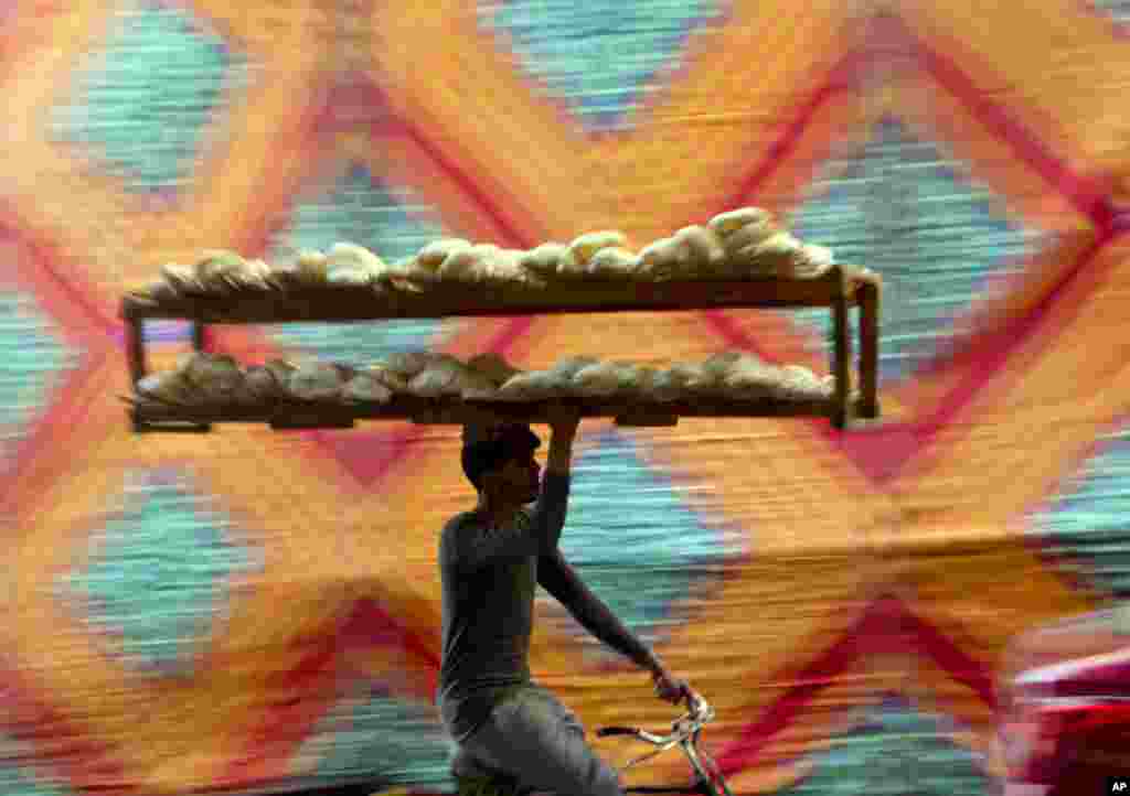 A vendor carries a bread tray while riding a bicycle, in Cairo, Egypt.