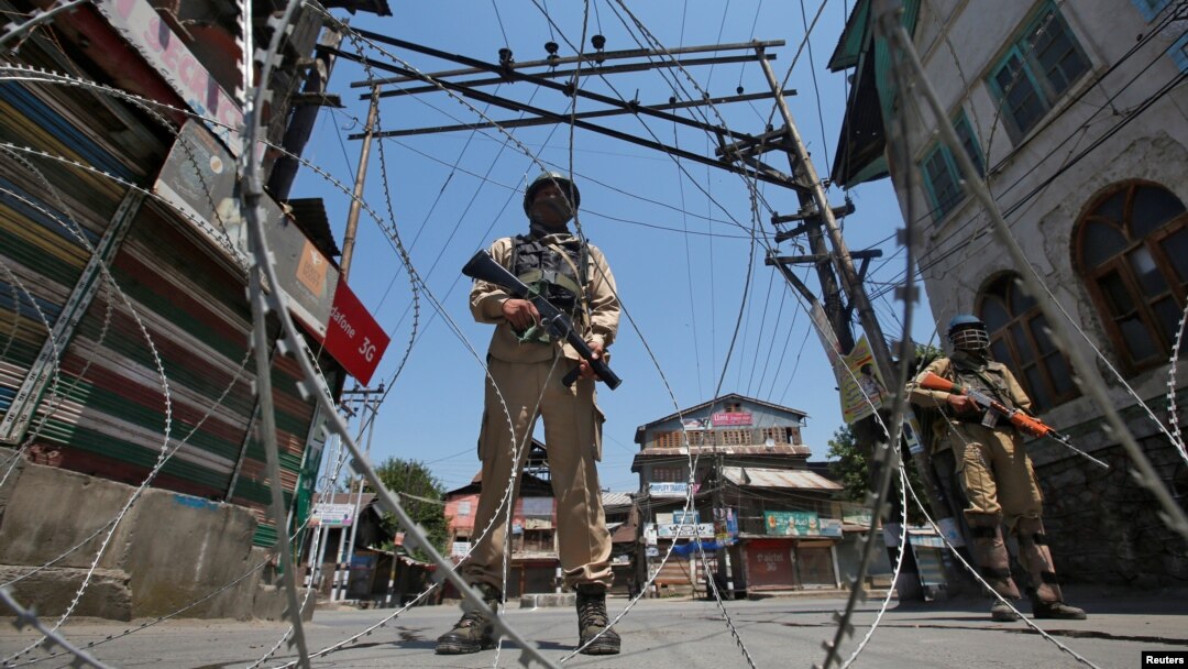 Indian policemen stand guard behind concertina wire during a strike called by separatists to mark the death anniversaries of chief cleric of Kashmir, Moulana Mohammad Farooq and Abdul Gani Lone, a Kashmiri separatist leader, in Srinagar, May 21, 2018.