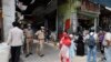 Policemen stand guard as people shop during a limited opening of small grocery stores amid the coronavirus pandemic, in Prayagraj, India, April 25, 2020.