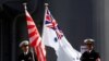 Crew members from the Japanese Maritime Self-Defense force ship Umigiri stand on deck between Japan's Self-Defense Force flag alongside an Australian flag before joint exercises in Australia. 