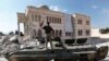 FILE - A Free Syrian Army soldier stands on a Syrian military tank in front of a mosque, which were damaged during fighting with government forces, in the Syrian town of Azaz, on the outskirts of Aleppo, Sept. 23, 2012.
