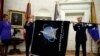 Chief of Space Operations at US Space Force Gen. John Raymond, center, and Chief Master Sgt. Roger Towberman hold the United States Space Force flag as it is presented in the Oval Office of the White House, May 15, 2020.