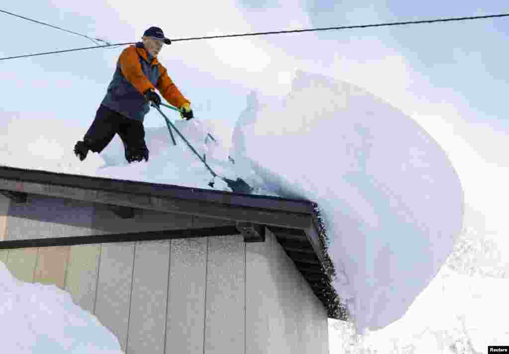 A man clears snow from a rooftop in Oishida, Yamagata Prefecture, Japan, in this photo taken by Kyodo.