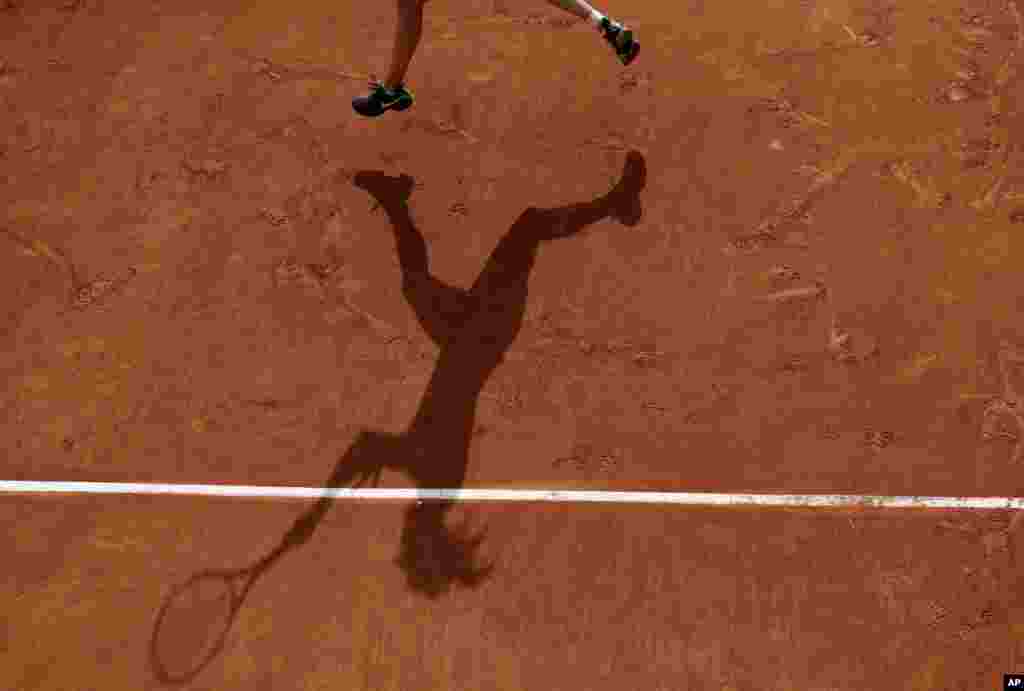 Canada's Eugenie Bouchard casts a shadow on the clay as she plays Japan's Risa Ozaki during their first round of the French Open tennis tournament at the Roland Garros stadium in Paris, France.