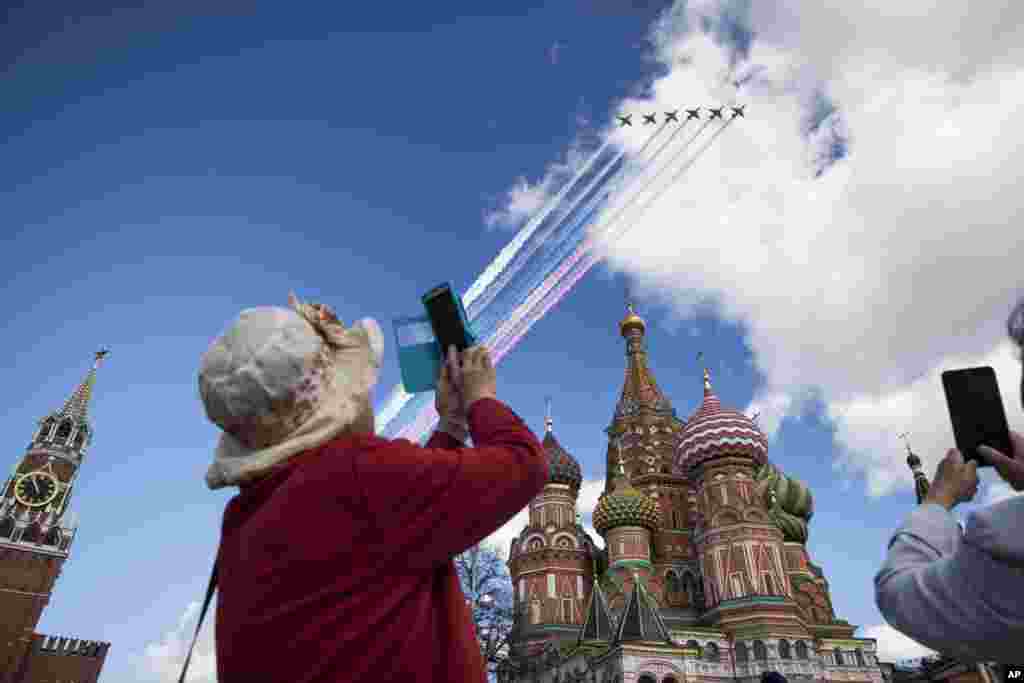 A tourist takes photos of Russian jets flying over the Kremlin during a rehearsal for the Victory Day military parade in Moscow.
