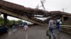 People walk under a destroyed railroad bridge over a main road leading into Donetsk, near the village of Novobakhmutivka, North of Donetsk, eastern Ukraine, July 7, 2014.