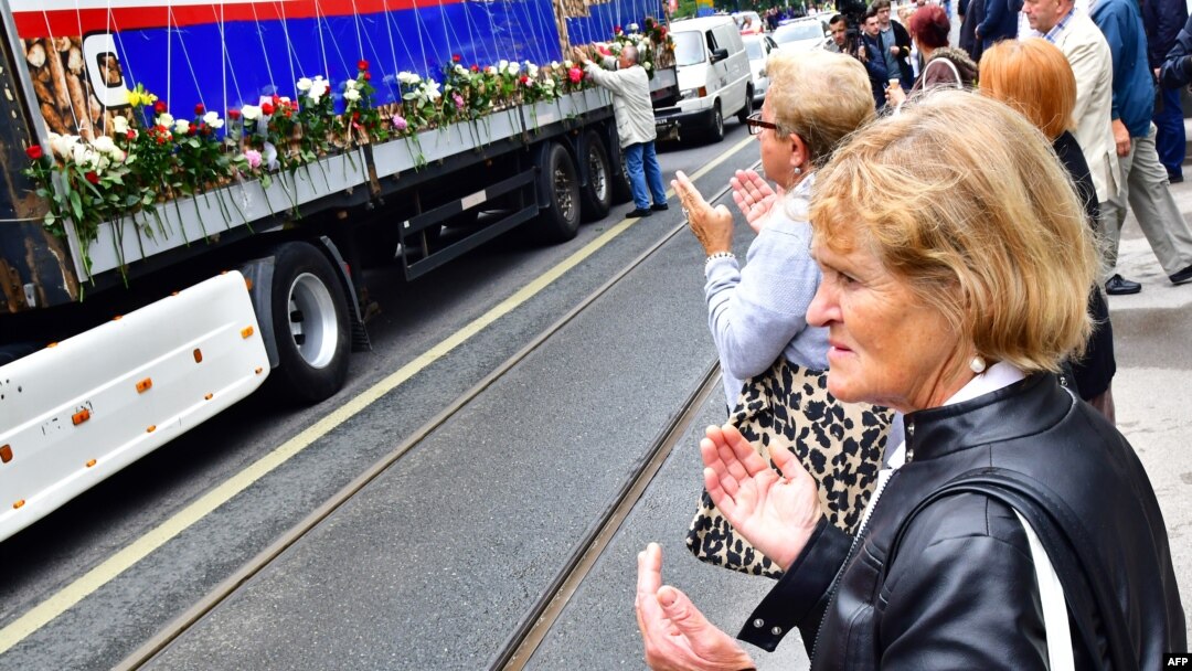 Bosnian Muslims, citizens of Sarajevo, pray near a truck, carrying the remains of 35 newly identified victims of Srebrenica massacre, while it makes a short stop in Sarajevo city center, July 9, 2018.