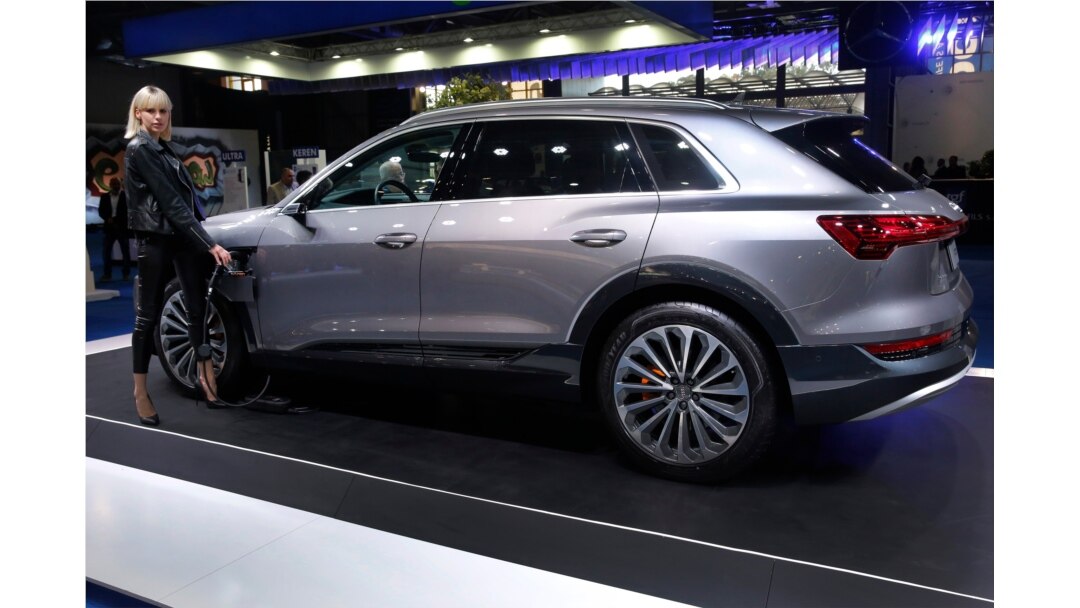 FILE - A model holds the power cable that charges the new electric Audi e-tron Quatro, displayed at the e-Motor show in Beirut, Lebanon, April 11, 2019.