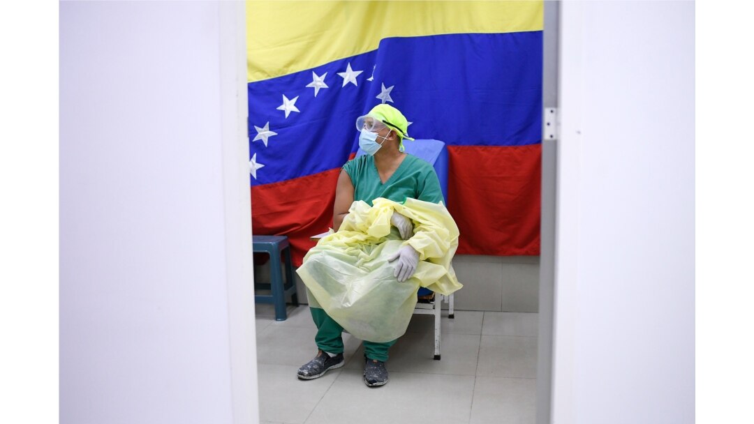 Backdropped by a national flag, a doctor waits to receive a dose of the Russian COVID-19 vaccine Sputnik V at the Ana Francisca Perez de Leon II public hospital in Caracas, Venezuela, Feb. 19, 2021.