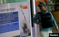 FILE - A passenger walks past a TV screen broadcasting a news report on North Korea's submarine-launched ballistic missile fired from North Korea's east coast port of Sinpo, at a railway station in Seoul, South Korea, Aug. 24, 2016.