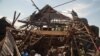 Men investigate the remains of a house struck hours earlier by deadly mortar fire, sparking angry protestors to take to the streets, in Goma, DRC, Aug. 24, 2013. 