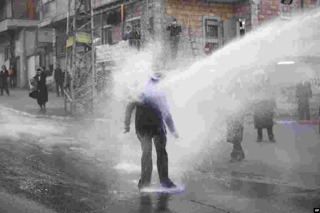 An ultra-Orthodox Jew gets hit by a police water canon during a protest against Israeli army conscription, in Jerusalem.