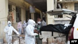 Medical staff in protective suits remove a dead body from a vehicle upon arriving at the Civil Hospital in Ahmedabad on Aug. 6, 2020, after a fire at Shrey Hospital killed eight coronavirus patients.