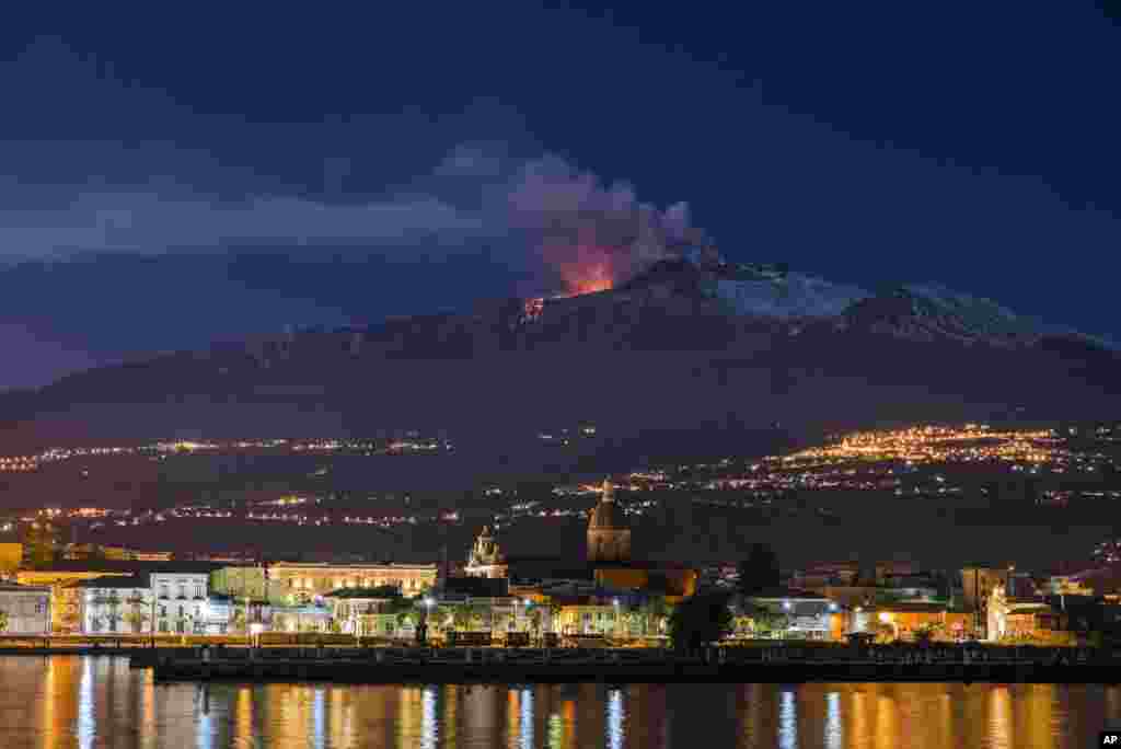 Mount Etna, Europe's most active volcano, spews lava as the Sicilian town of Riposto, Italy, is visible in foreground, during an eruption.