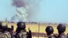 Turkish soldiers watch smoke billow from the Syrian town of Kobani following the attacks by IS militants as seen from the Turkish side of the border in Suruc, June 25, 2015.