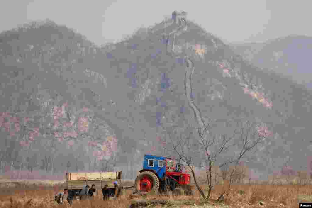 North Korean farmers work in a field as a section of the Great Wall is seen on the Chinese side of the Yalu River, north of the town of Sinuiju in North Korea and Dandong in China's Liaoning province.