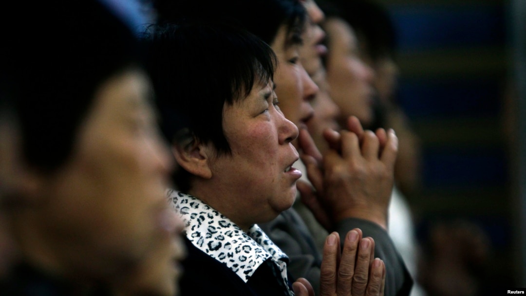 FILE - A woman prays with other villagers during a mass in the morning at the Liuhe Catholic Church in Liuhe village on the outskirts of Qingxu county, northern China's Shanxi province, Sept. 11, 2011.