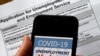 FILE - A COVID-19 Unemployment Assistance Updates logo is displayed on a smartphone against the backdrop of an application for unemployment benefits, in Arlington, Virginia.