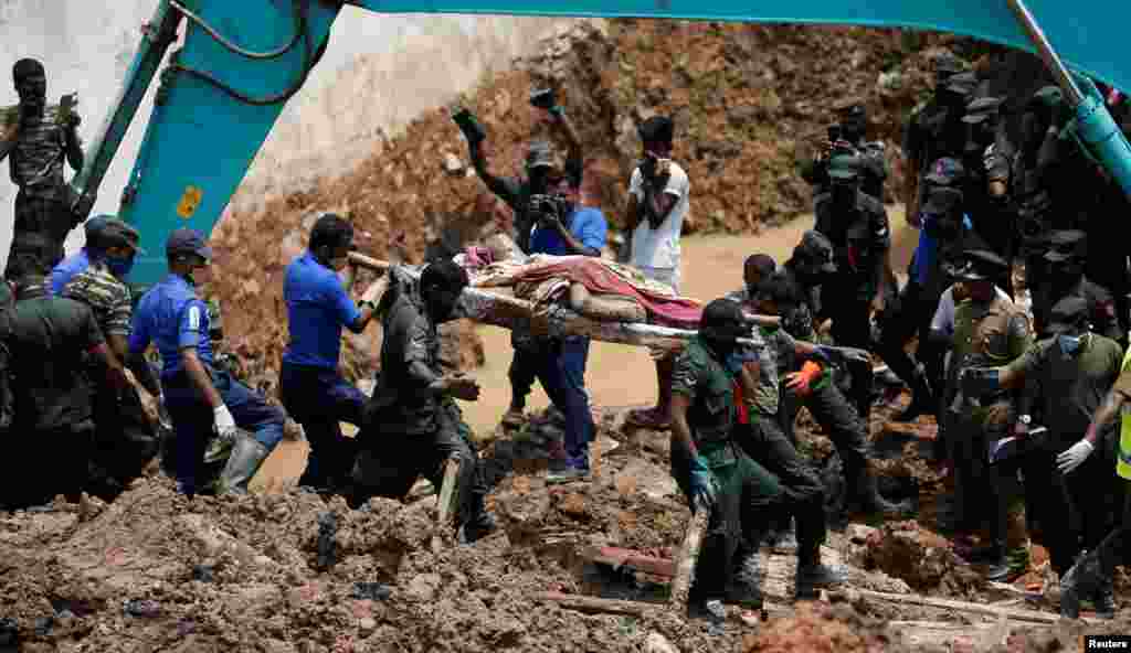 Members of the military carry a dead victim during a rescue mission after a garbage dump collapsed and buried dozens of houses in Colombo, Sri Lanka.