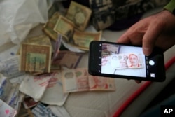 A member of the media uses his mobile phone to take pictures of belongings including banknotes of different currencies on a bed inside the flat where a suspect of New Year's Day nightclub attack was arrested, in Istanbul, Janv. 17, 2016.