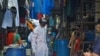 A worker wearing a 'Smart Helmet' thermoscanner that measures the temperature of people at a distance, screens residents in a slum Mumbai, India, July 23, 2020.