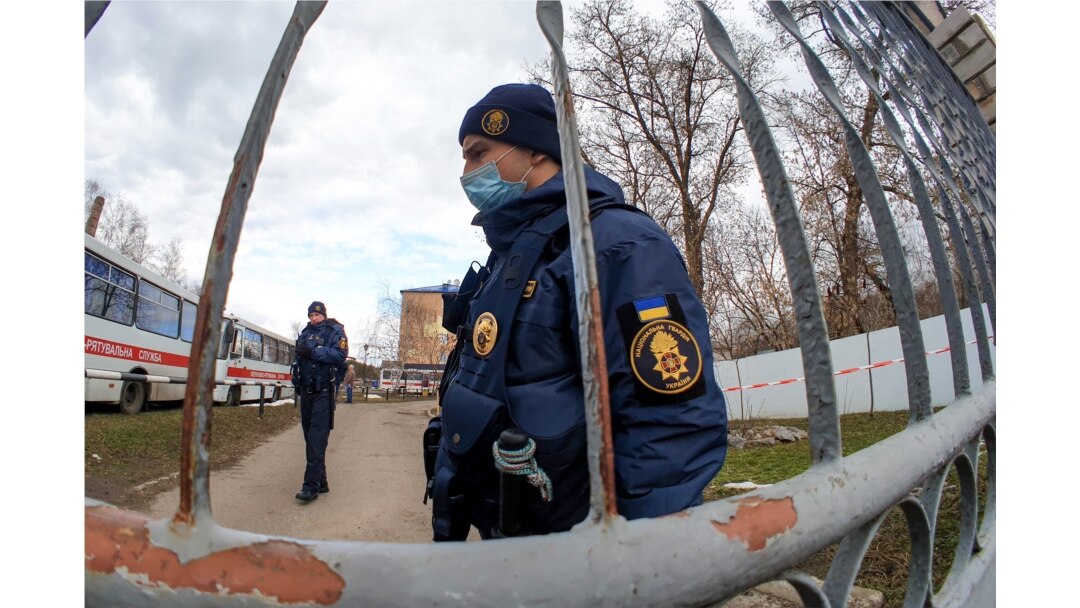 Ukrainian National Guard servicemen patrol by the gate of a military medical facility where evacuees from coronavirus-hit China are quarantined, in the town of Novi Sanzhary, Poltava region, Ukraine, Feb. 21, 2020.