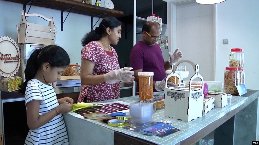 Sri Themudu, right, packages gift baskets for customers along with his wife, Praveena Sarva, and 7-year-old daughter, Diyaa. It’s a seasonal business for Deepavali, the Indian festival of lights. (Dave Grunebaum/VOA)