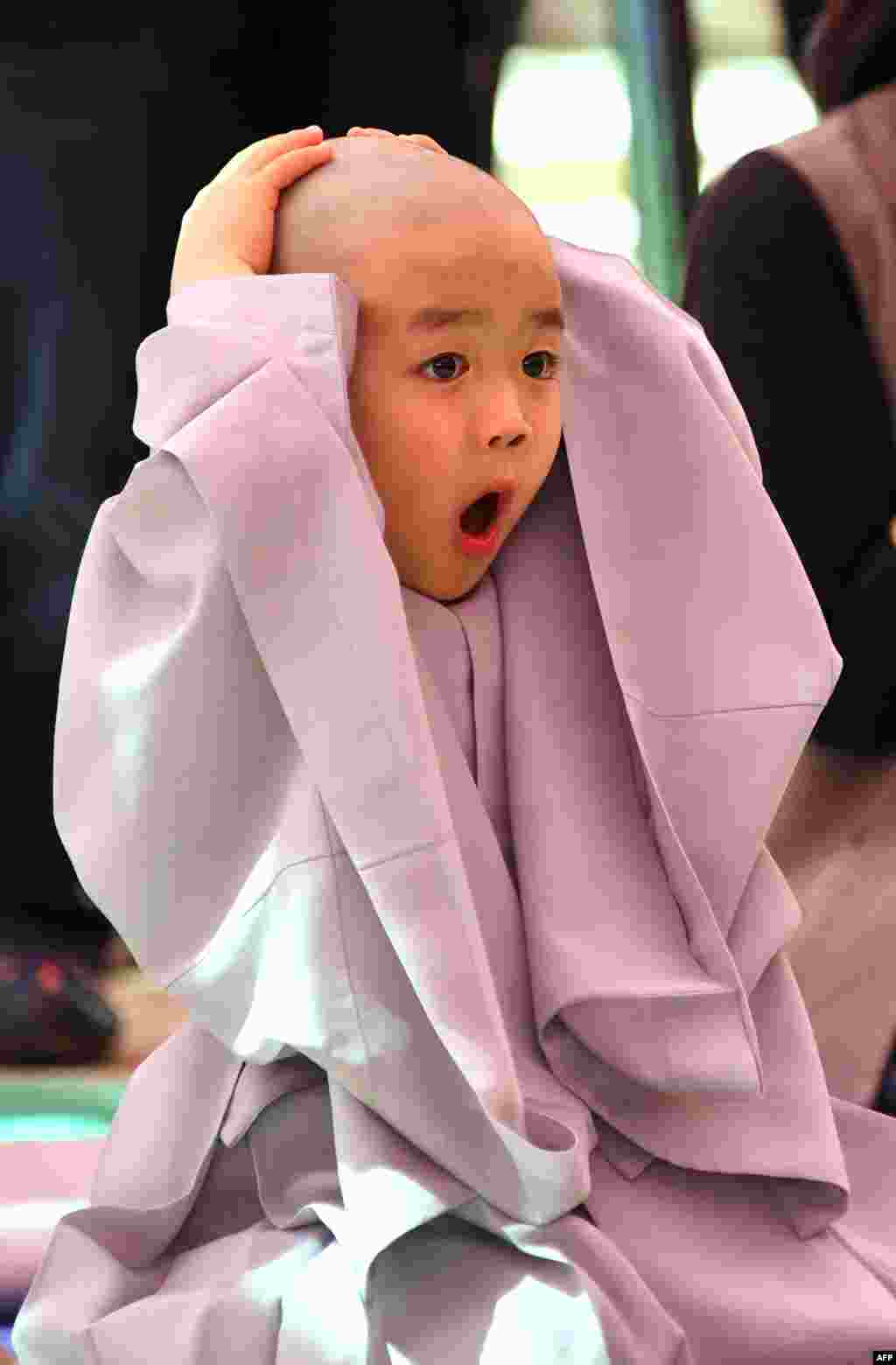 A child reacts after having his head shaved by Buddhist monks during a ceremony entitled 'Children Becoming Buddhist Monks', at the Jogye temple in Seoul, South Korea.