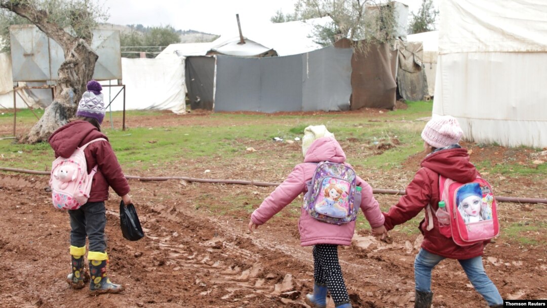 Internally displaced Syrian children walk in mud near tents at a camp in northern Aleppo near the Syrian-Turkish border.