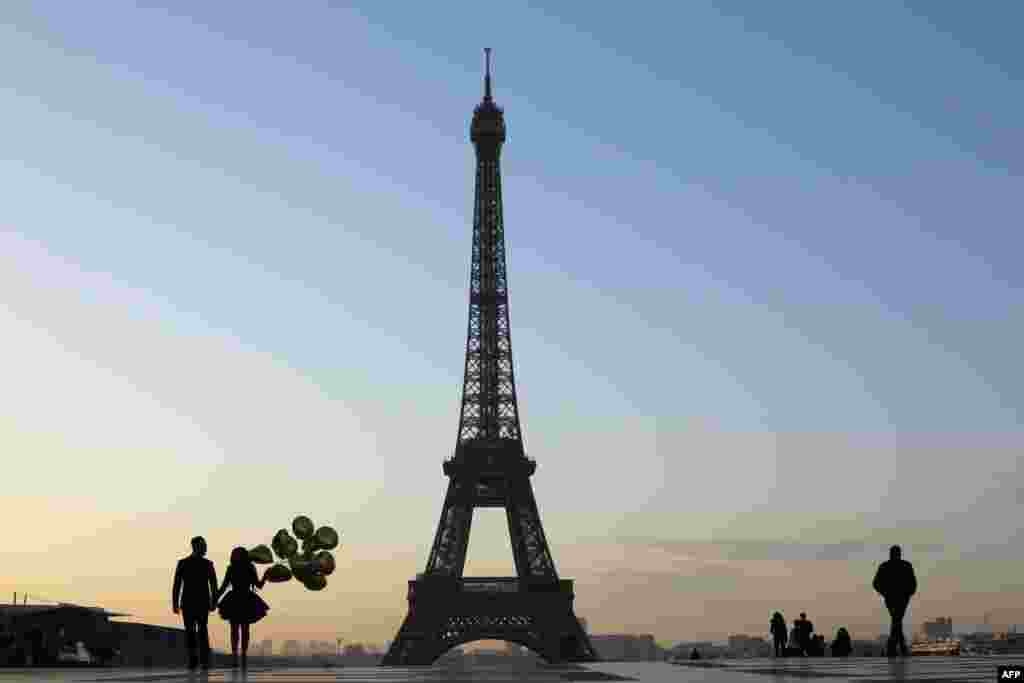 Tourists and a young married couple are pictured at sunrise on the Esplanade du Trocadero near the Eiffel Tower in Paris, France.