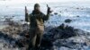 FILE - A Ukrainian soldier shows pieces of shrapnel in a crater left by an explosion in Avdiivka, Ukraine, Jan. 31, 2017.