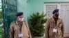 FILE - Indian police officials wear protective masks as they stand guard at an entrance of Himachal Pradesh Cricket Association.