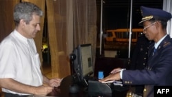 French architect Patrick Devillers stands in front of an immigration officer at the Phnom Penh International Airport before departing Cambodia for China, July 17, 2012. 